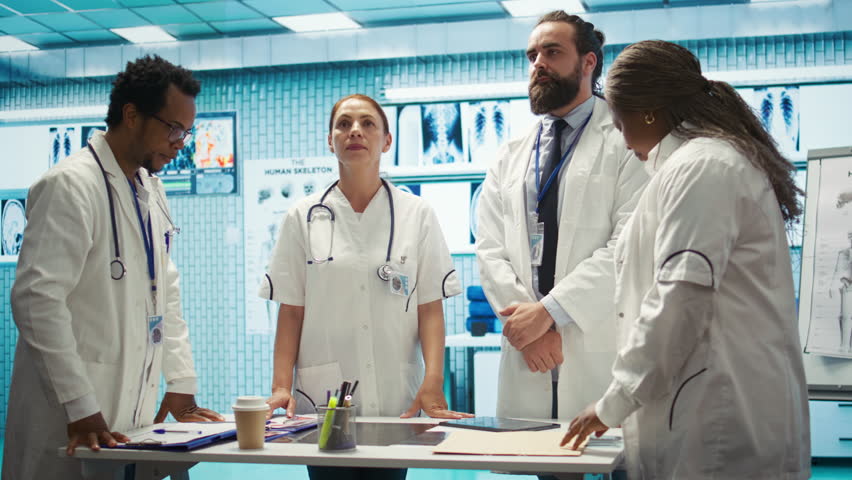 Team of medical specialists examining diagnostic data and hospital records, using a holographic image in cabinet. Experts looking into treatment plans on hologram at clinic. Camera B. - Powered by Shutterstock - Get 15% off with code: PIKWIZARD15