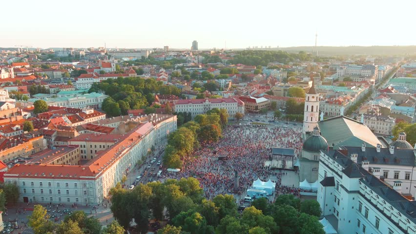 Aerial view of crowds celebrating Lithuanian Statehood Day. Lots of people singing national anthem of Lithuania on Cathedral square. Vilnius Old town landscape on bright sunny summer day. Lithuania.
