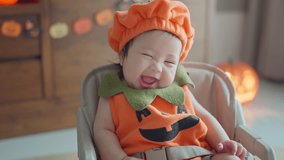 Happy cute asian newborn baby girl dressed in Halloween jack o lantern costume during sit on chair having fun and celebrating Halloween at home - Powered by Shutterstock - Get 15% off with code: PIKWIZARD15