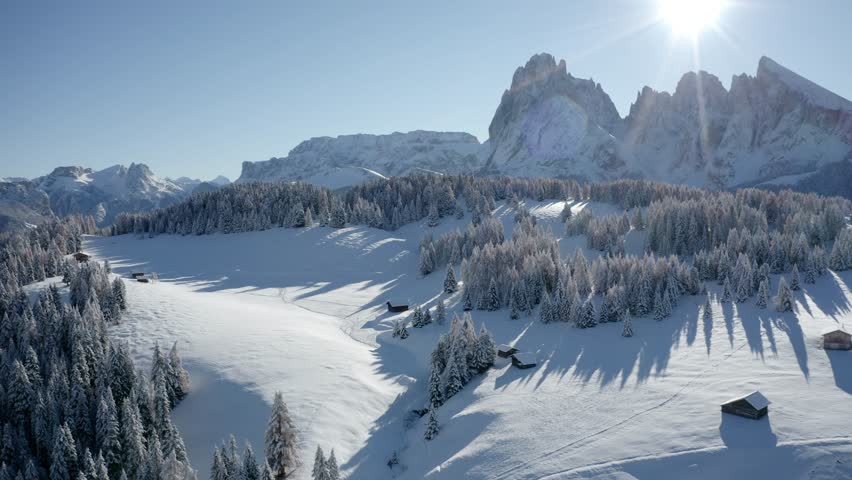 4k drone flight moving to the side footage (Ultra High Definition) of  Alpe di Siusi village with Plattkofel peak on background. Sunny morning view of Dolomite Alps. Cold winter scene of Ityaly, Europ