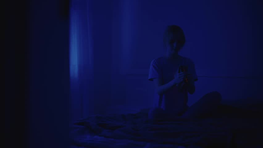 A girl reads a book at night. Night reading. Blue light. Night. Scary atmosphere. Red light from a book. Cinematic video. Vintage optics. Atmospheric video