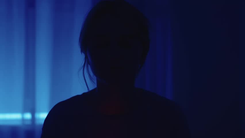 A girl reads a book at night. Night reading. Blue light. Night. Scary atmosphere. Red light from a book. Cinematic video. Vintage optics. Atmospheric video