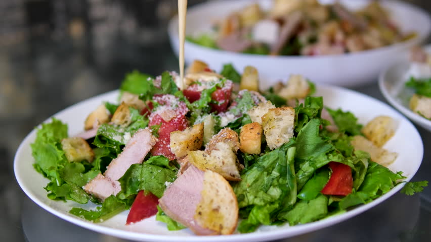 Close up shot of cooking Caesar salad inside deep cooking bowl. Chef cooking Caesar. Cooking process.