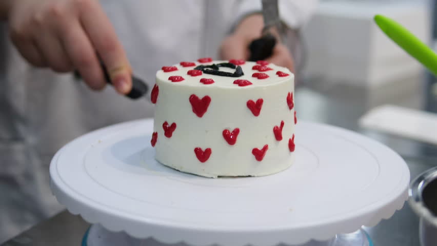 cake with red hearts pastry chef decorates a cake with red heart-shaped cream for Valentine