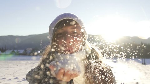 SLOW MOTION: Young woman blowing snow