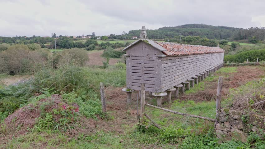 Camera panning around a traditional stone granary in rural countryside