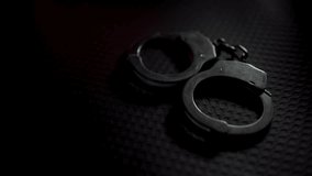 
Steel handcuffs of a police officer rest on a black surface, gleaming with a red reflection. A sturdy chain links the cuffs together, symbolizing power and control. The scene exudes a somber and inte - Powered by Shutterstock - Get 15% off with code: PIKWIZARD15