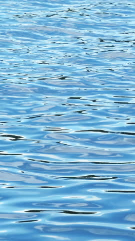 Close-up of beautiful ripples on blue water. Blue ripples on surface of sea water. Reflection of blue colors of sky on surface of water ripples