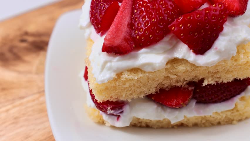 Eating strawberry shortcake with fresh strawberries and whipped cream with a fork close up