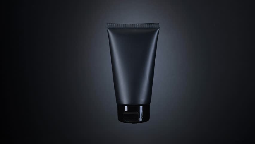 Black cosmetic tube rotating and beautifully illuminated against a dark backdrop, ideal for captivating beauty promotion