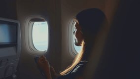 Asian woman using headphone listen to music while sitting in airplane. Attractive female traveler feel happy and relax, listen to podcast on smartphone while travel during vacation trip by aeroplane. - Powered by Shutterstock - Get 15% off with code: PIKWIZARD15
