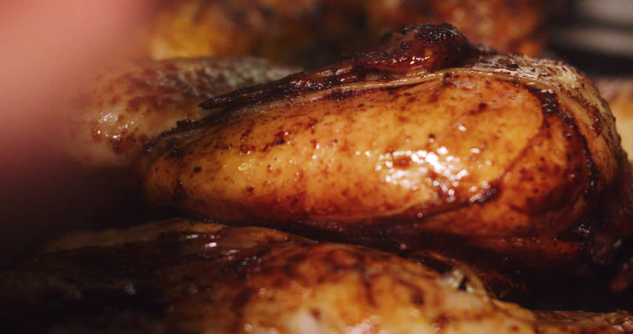 Beautiful close-up shot of a roasted chicken being sprayed with juice or spice seasoning to make it juicier with a brush in a restaurant kitchen.