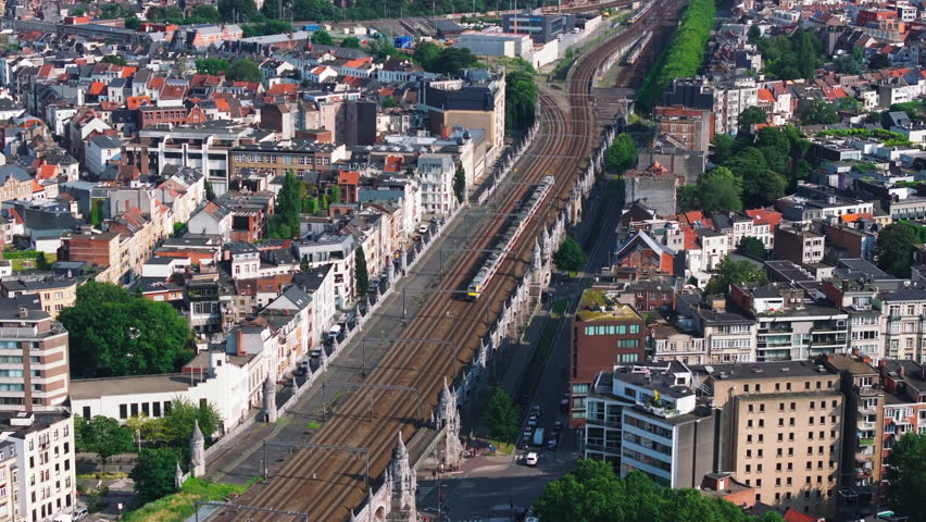 Yellow train approaches Antwerp Central Station, showcasing a stunning cityscape filled with vibrant architecture and bustling urban life in a picturesque summer setting