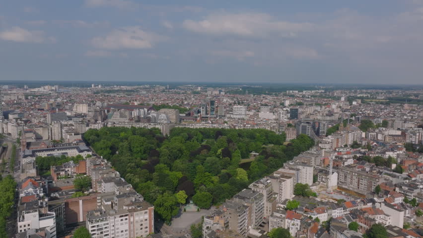 Aerial view of a large park in Antwerp, Belgium. The camera pans slowly across the park, showing the lush green trees and the pond
