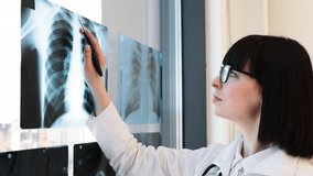 Female doctor in white coat analyzing X-ray images with tablet in office. Healthcare professional working indoors, reviewing patient medical scans for diagnosis. - Powered by Shutterstock - Get 15% off with code: PIKWIZARD15
