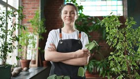 Running of own business. Young woman florist wearing apron in botanical store with green plants. Happy small business owner working at flower shop standing surrounded by plants. Small business - Powered by Shutterstock - Get 15% off with code: PIKWIZARD15