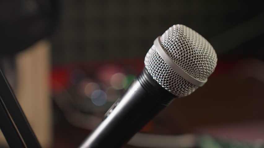 Close-up shot of a microphone on a stand with a blurred background, highlighting the microphone as the focal point. with the blurred background adding depth and context