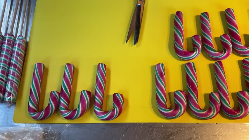 Christmas sugar sticks at table with a yellow background and a bunch of green, red and white striped candy canes