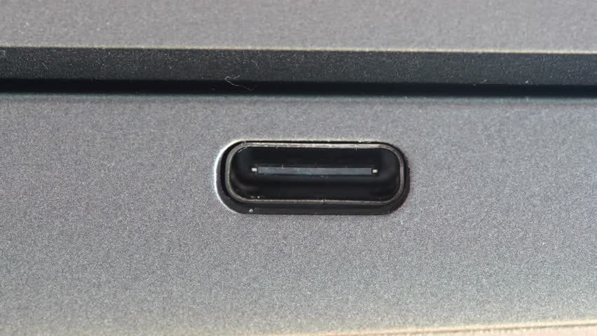 USB-C data charging monitor output port input on the side of a modern laptop computer, macro shot, extreme closeup detail, nobody, front view. USB C connection standard simple concept, no people