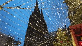A Christmas tree with many red and green ornaments at Christmas market in Germany. The tree is lit up with lights and the sky is blue - Powered by Shutterstock - Get 15% off with code: PIKWIZARD15