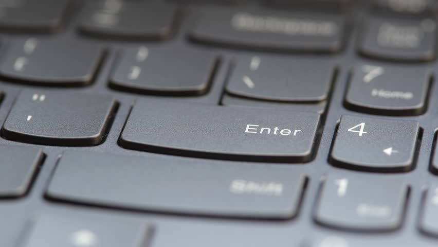 Man pressing the enter key on a modern laptop computer keyboard, macro detail closeup, user POV, shallow DOF, one person. Sending a message, buying something accepting rules, running a program concept