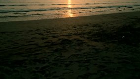 Drone aerial views nature scenes, an ocean setting, a dark, empty beach, and foamy waves with a man standing in the water during sunset, tilt-up - Powered by Shutterstock - Get 15% off with code: PIKWIZARD15