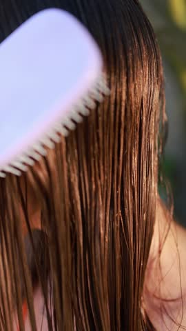 A woman carefully brushes her wet hair after a refreshing outdoor shower, ensuring smooth and healthy strands as part of her hair care routine