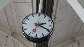 Large public clock hanging from a modern structure with visible metal beams and cables, indicating time, possibly in a station or urban setting, with clear hour, minute, and second hands. The clock  - Powered by Shutterstock - Get 15% off with code: PIKWIZARD15