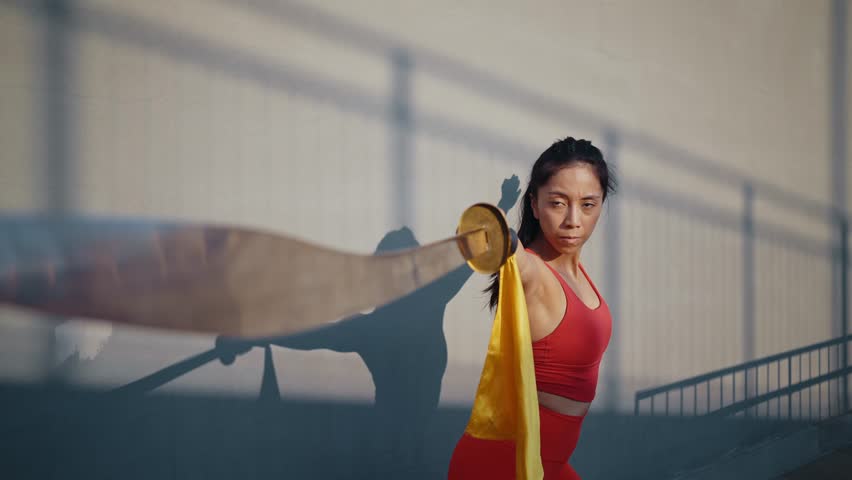 Young woman training in kung fu wushu martial arts outdoor with weapons and swords.