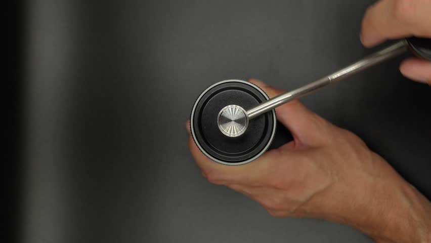 top-down view of hands carefully operating a manual coffee grinder. The circular motion of the hand crank is captured in mid-action, emphasizing the precision and attention to detail required for