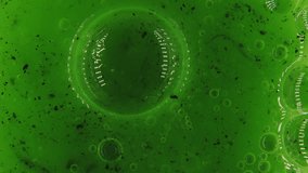 This abstract macro image features a close-up view of a green liquid filled with small bubbles and black particles, creating a textured and organic composition. The varying shades of green, along with - Powered by Shutterstock - Get 15% off with code: PIKWIZARD15