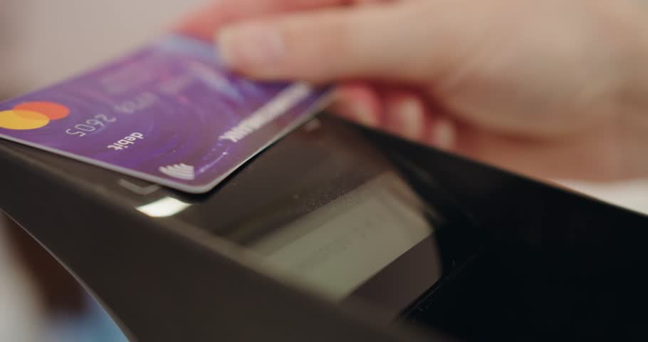 A close-up image showing a person swiping a credit card through a payment terminal, highlighting the ease and security of electronic transactions. Close-Up of Credit Card Being Swiped at a Terminal