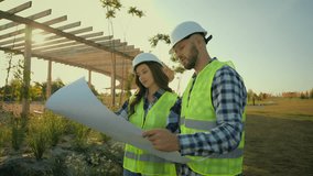 Female male workers Caucasian woman man builders girl guy engineers discussing installation talking environmental plan technicians analyzing blueprint business agriculture ecology project field park - Powered by Shutterstock - Get 15% off with code: PIKWIZARD15