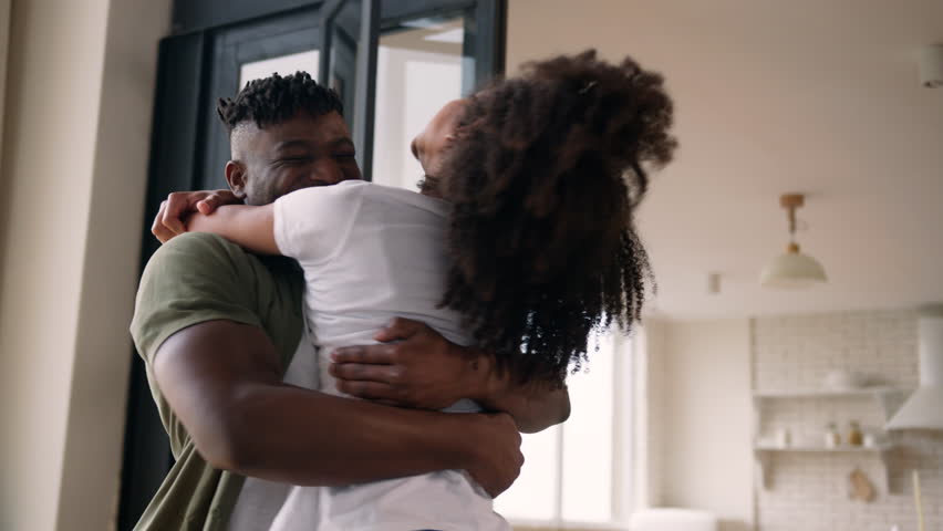 African American man woman married couple love bonding affection happy boyfriend girlfriend hugging happiness celebrate wedding propose engage joyful guy spinning girl around at home embrace together