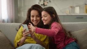 Happy playful Caucasian little girl child kid jumping sofa embracing female woman using mobile phone daughter mom family shopping online ordering delivery scrolling cellphone browsing internet at home - Powered by Shutterstock - Get 15% off with code: PIKWIZARD15