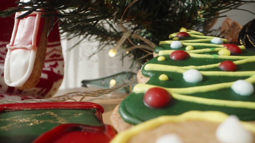 Gingerbread Cookies Decorated for Christmas, Including a Gingerbread Man and Christmas Tree, Set Against Festive Background. Dolly slider, close up.