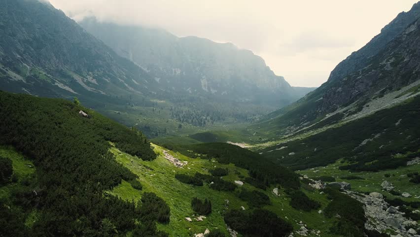 Drone footage of stunning green landscape surrounded by massive peaks in High Tatras, Slovakia