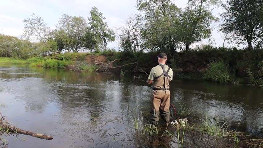 Man catching pike, perch, salmon and trout on a river with lures and fly fishing setup