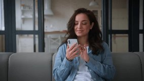 Happy smiling positive carefree cheerful Caucasian woman girl female lady at home at couch browsing scrolling using mobile phone smartphone relax chat social media app gadget addict shopping online - Powered by Shutterstock - Get 15% off with code: PIKWIZARD15