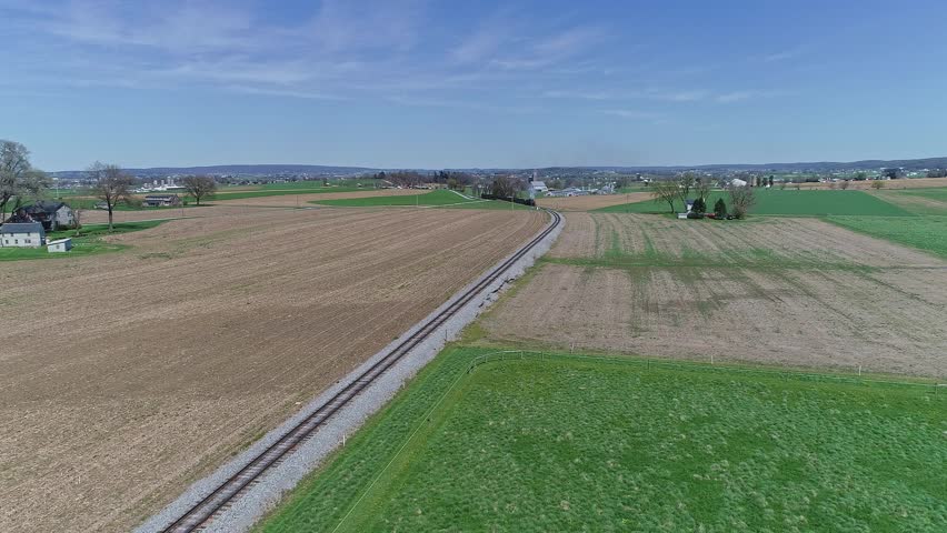 Tranquil Rural Landscape With Railroad Tracks in a Green Field Under Clear Blue Sky