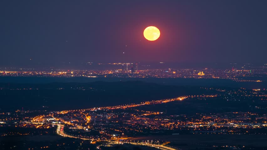 Timelapse of full moon rinsing over Madrid city and highway with traffic lights during blue hour early night