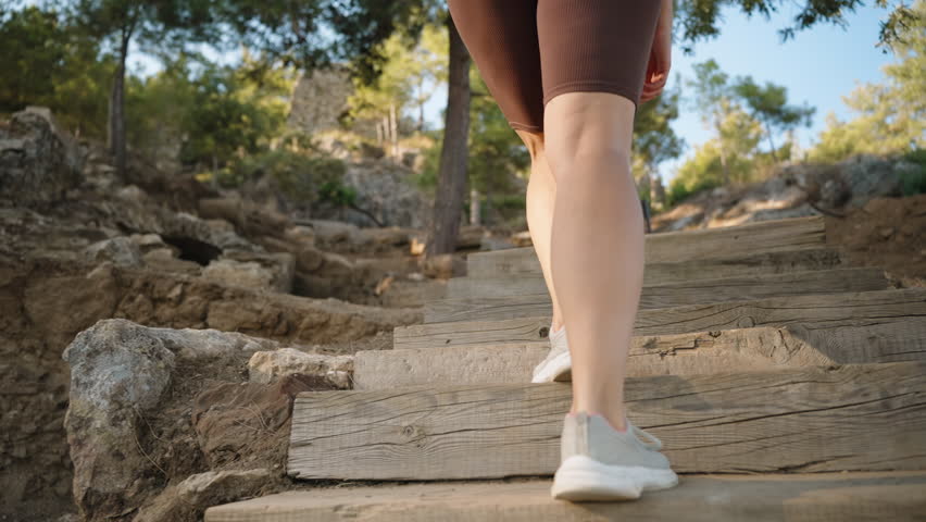 Slow-Motion Sequence Follows a Woman Ascending Wooden Steps, Her Footsteps Echoing in the Tranquil Forest Setting.