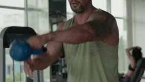 A muscular man with tattoos performing a kettlebell swing exercise in a modern gym, displaying strength and determination. - Powered by Shutterstock - Get 15% off with code: PIKWIZARD15