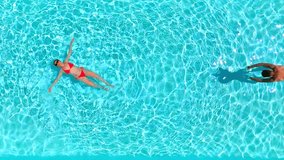 Top down view as a man dives into the pool while woman is laying on her back - Powered by Shutterstock - Get 15% off with code: PIKWIZARD15