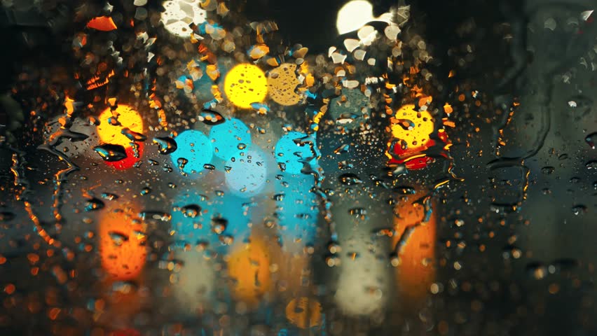 Lights of the evening city and passing cars through a wet rainy window.