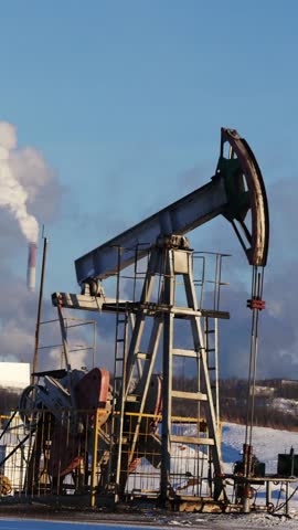 Oil pump jack extracting crude oil on a winter day