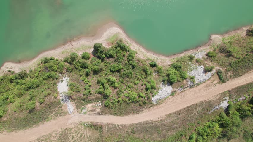 Birds eye view looking down from drone shot and aerial landscape of Ohio metro park along lakeside beach and water, along with various trails, sidewalks, and pathways through forest trees and woods
