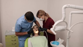 Dental assistant, Dental tools, Tooth check. Dentist in blue scrubs is examining patient's teeth with help from dental assistant in red scrubs. - Powered by Shutterstock - Get 15% off with code: PIKWIZARD15