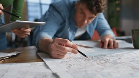Skilful colleagues creating blueprint at open space office closeup. Smiling business partners drawing at architect plans indoors. Happy company coworkers looking paper discussing project at cabinet  - Powered by Shutterstock - Get 15% off with code: PIKWIZARD15
