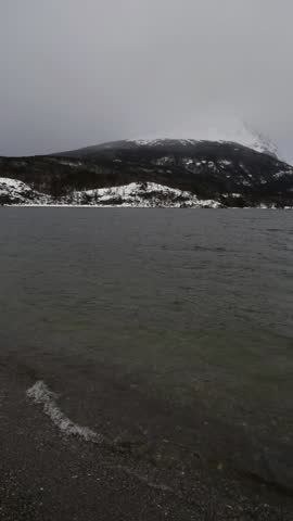 Stunning Winter Scene in Ushuaia: Snowy Mountain Landscape with Lagoon, Cloudy Sky, and Soaring Bird - Natural Beauty in Tierra del Fuego Sound on